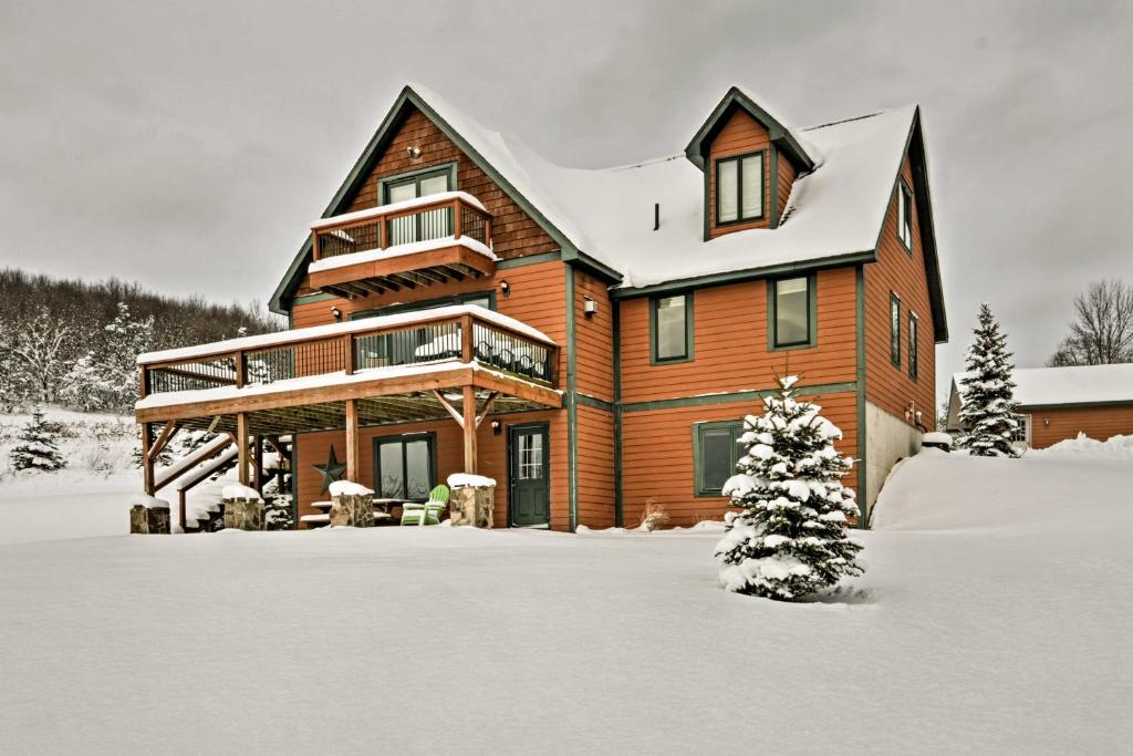 une maison en bois dans la neige avec un arbre de Noël dans l'établissement Mountaintop Ellicottville Home 7 Mi to Ski Resort, à Ellicottville