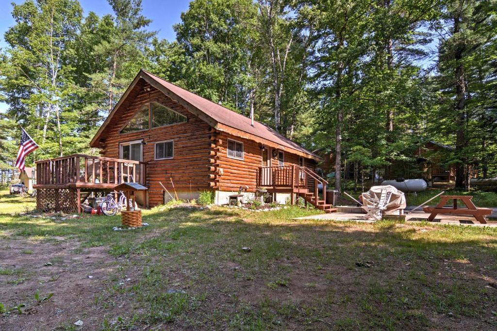 eine Blockhütte mit einer Veranda und einer Terrasse in der Unterkunft Cozy Manistique Cabin with Deck, Grill and Fire Pit! in Manistique