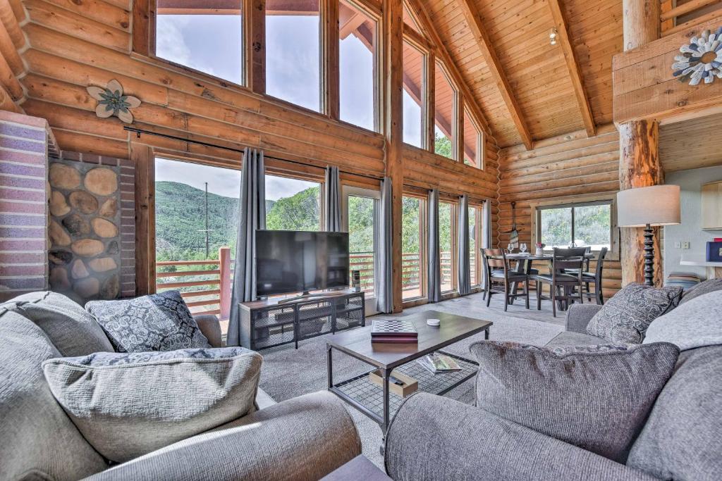 a living room with couches and a television and a table at Spacious Hilltop Cabin with Deck and Scenic Views! in Eden