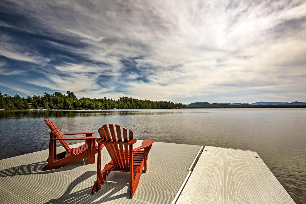 Restored Historic Lakefront Home with Panoramic Views في Lake Clear: كرسيين وطاولة على مرسى على بحيرة
