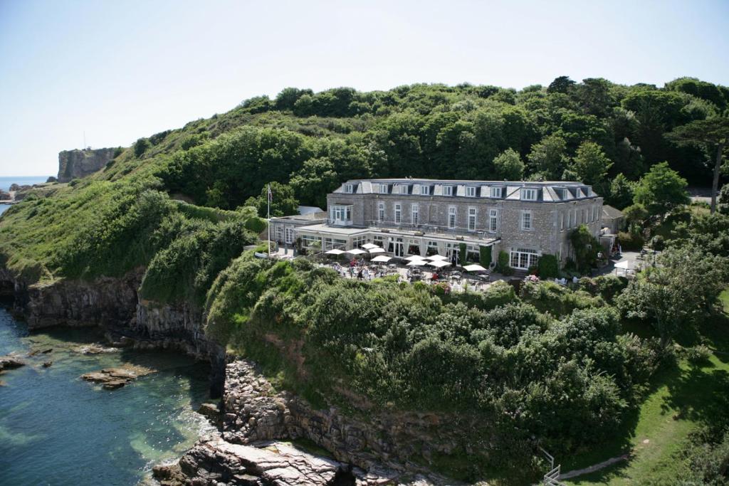 - un bâtiment sur une falaise à côté d'une nappe d'eau dans l'établissement Berry Head Hotel, à Brixham