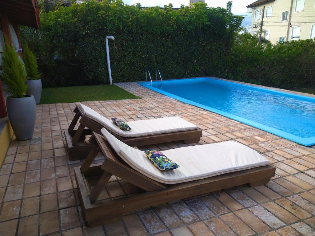 un patio con 2 tumbonas junto a una piscina en Willy's Holiday Home, en Florianópolis