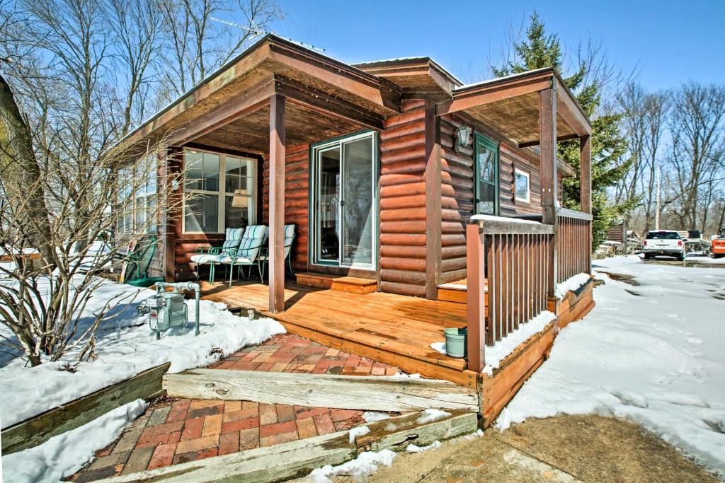 a small log cabin with a porch in the snow at Fort Atkinson Cottage on Lake Koshkonong with Deck! in Fort Atkinson