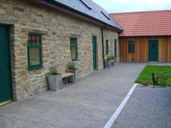 un edificio de piedra con un banco delante en Park Farm, en Gateshead