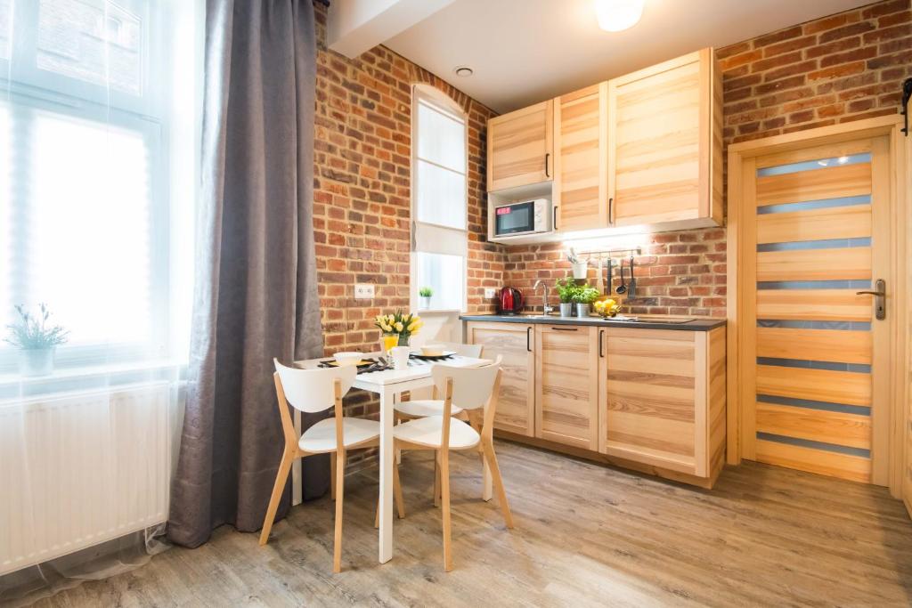 uma cozinha com uma mesa e cadeiras e uma parede de tijolos em UNO Apartaments em Katowice