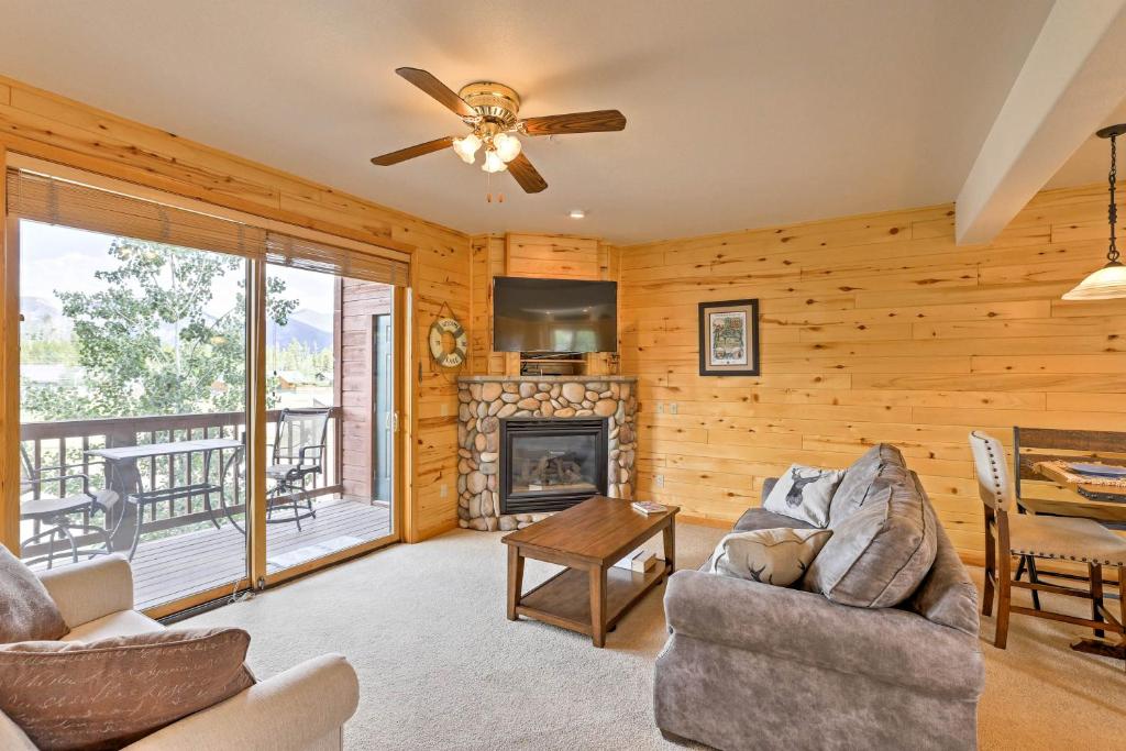 a living room with a fireplace and a ceiling fan at 7 Mi to National Park Grand Lake Condo with Deck! in Grand Lake