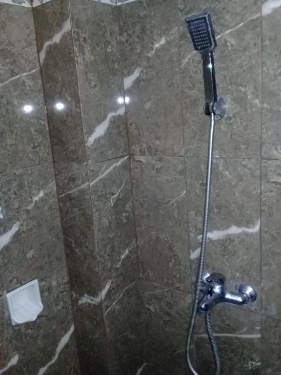 a shower in a bathroom with a stone wall at RF Hotel in Puncak
