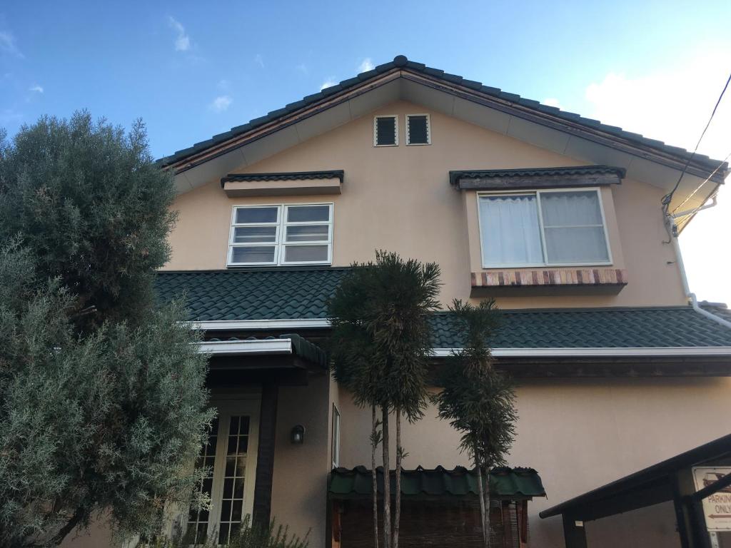 a house with palm trees in front of it at AbbeyRoad Inn Seika in Seika