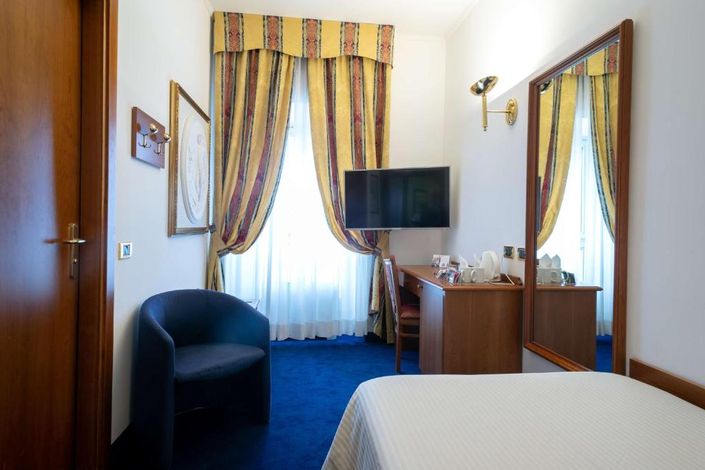a hotel room with a bed and a chair and a desk at Hotel Cappello D'Oro, BW Signature Collection in Bergamo