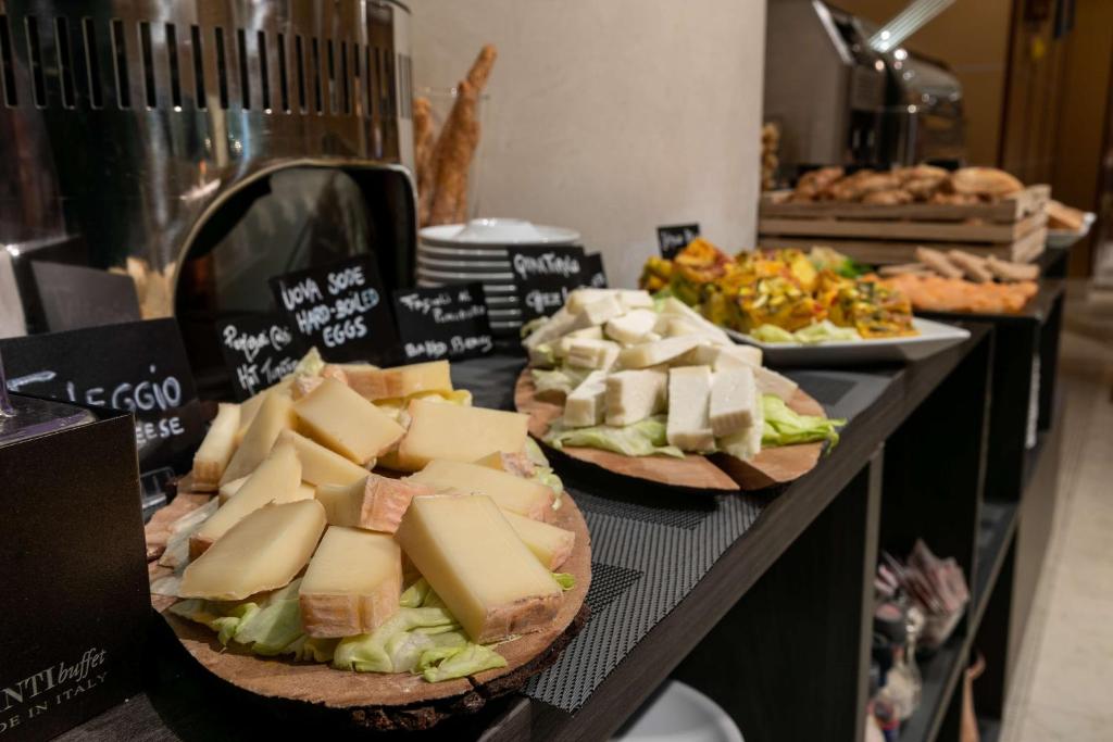 a table with plates of cheese and sandwiches on it at Hotel Cappello D'Oro, BW Signature Collection in Bergamo