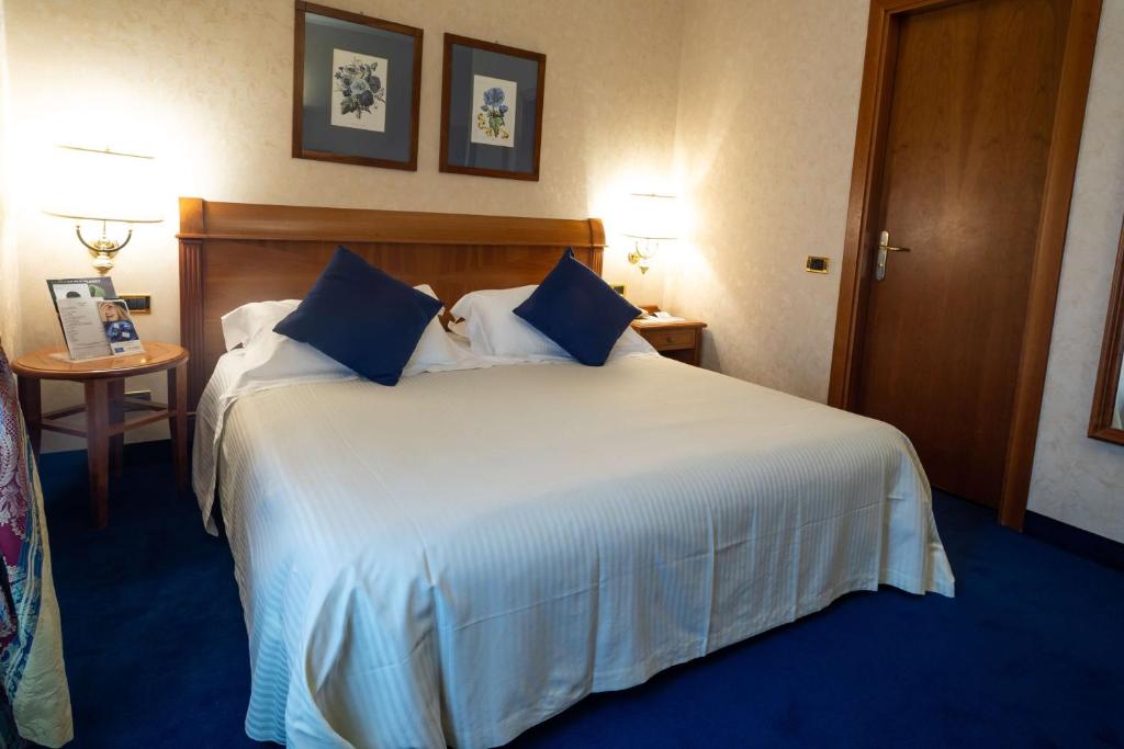 a bedroom with a large white bed with blue pillows at Hotel Cappello D'Oro, BW Signature Collection in Bergamo