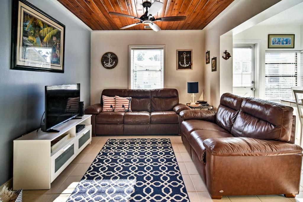 a living room with a leather couch and a television at Indian Shores Cottage with Cabana - Steps to Beach! in Clearwater Beach