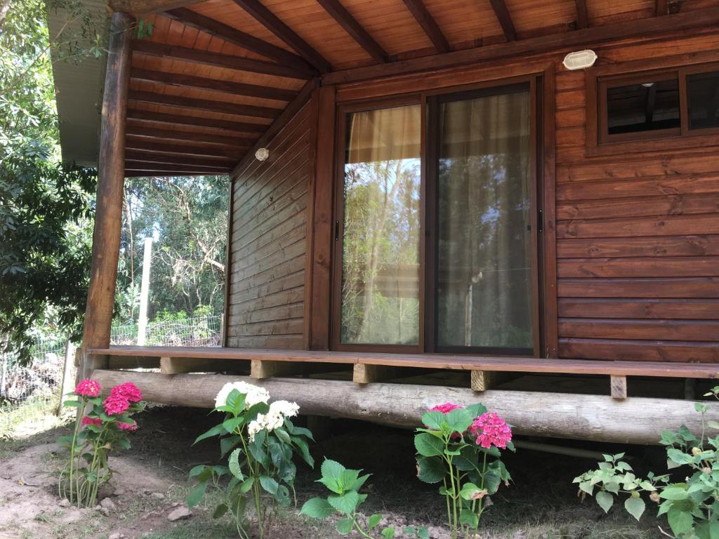 een houten huisje met bloemen op de veranda bij Los Quetzales in Maldonado