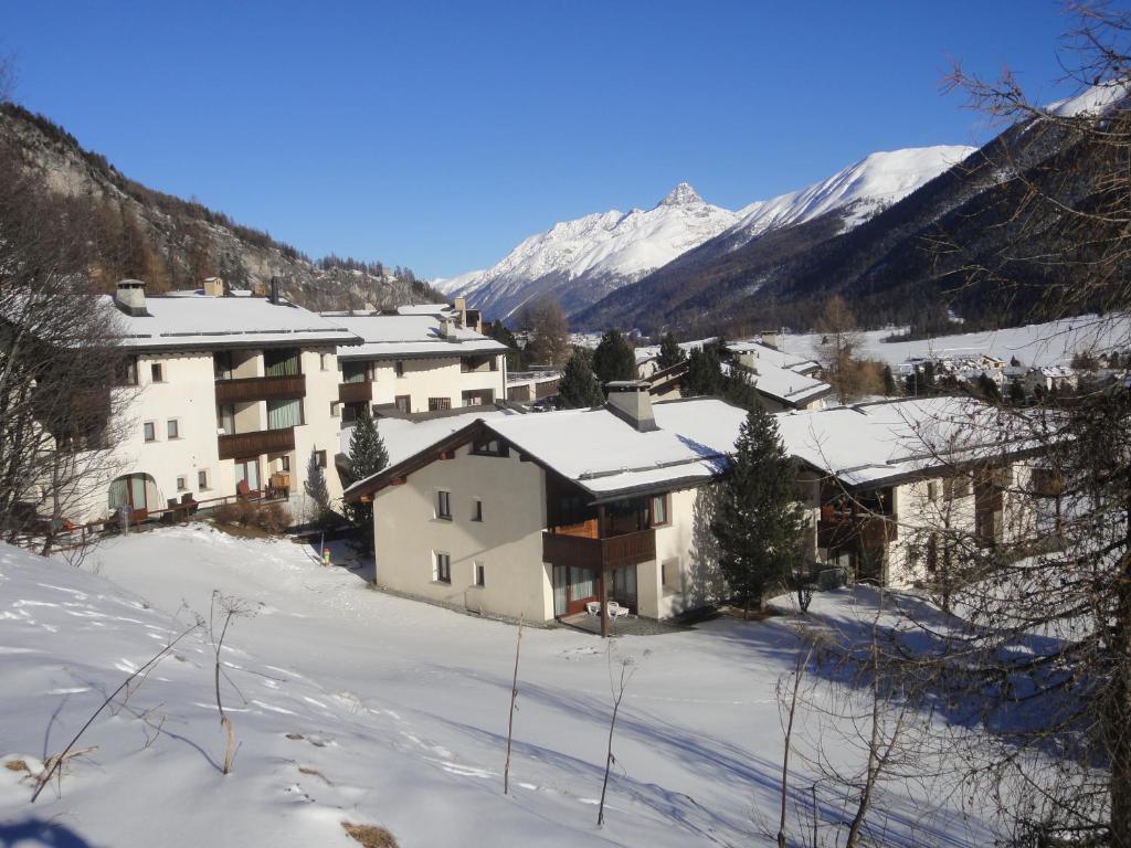 eine Gruppe von Gebäuden im Schnee mit Bergen in der Unterkunft Residenz La Mora in La Punt-Chamues-ch