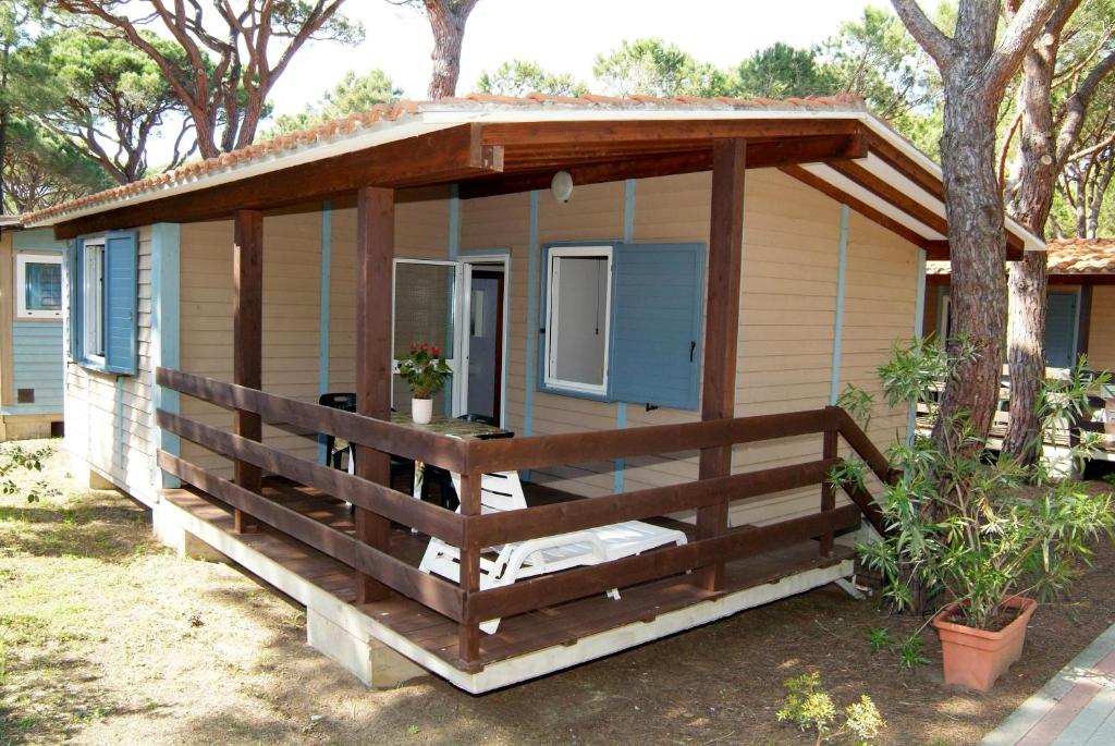 a tiny house with a porch and a fence at Camping Village Il Sole in Marina di Grosseto