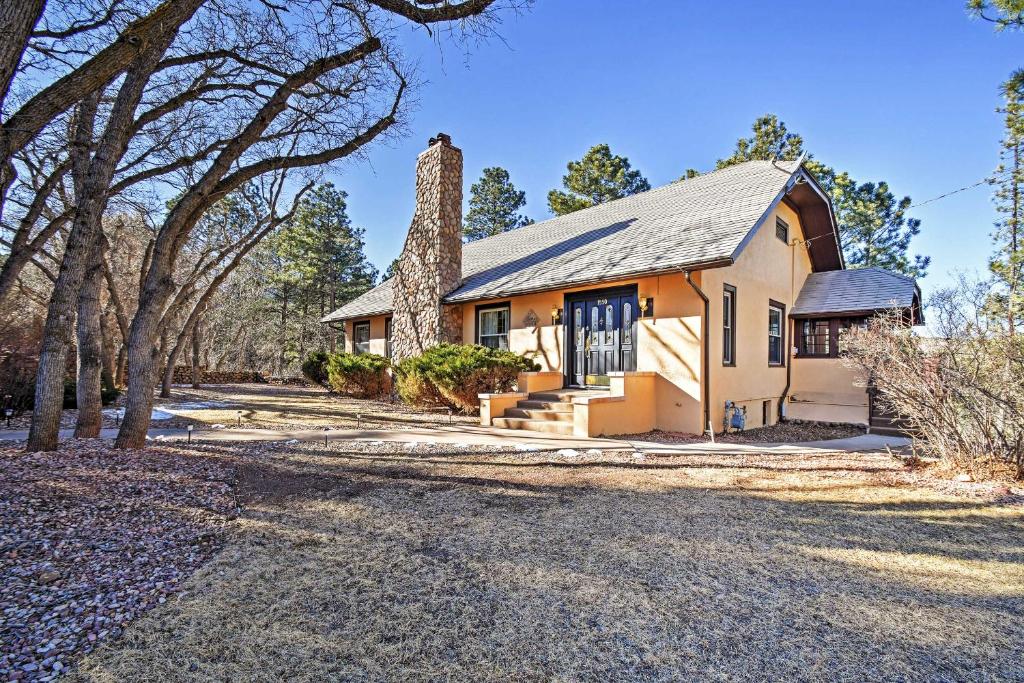 una casa antigua con chimenea de piedra y árboles en Inviting Colorado Springs House with Spacious Deck! en Colorado Springs