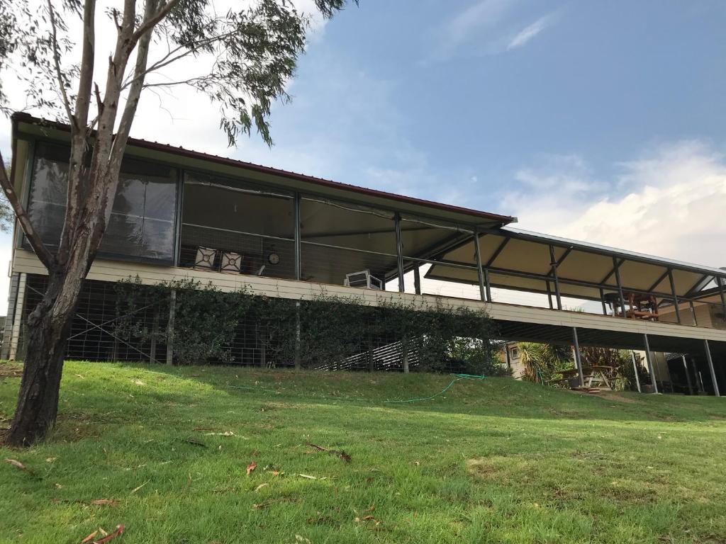 un gran edificio con ventanas de cristal y un árbol en Riverside Farm Retreat, en Eulah