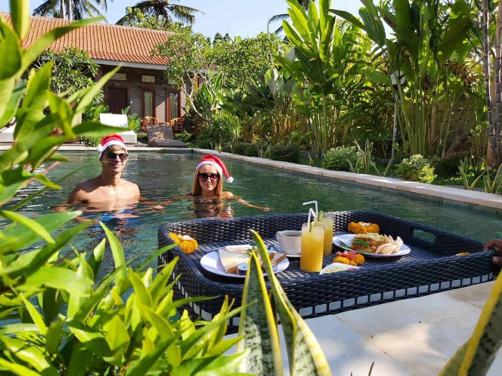two people in a swimming pool with a table of food at Ayuna Family Ubud in Ubud