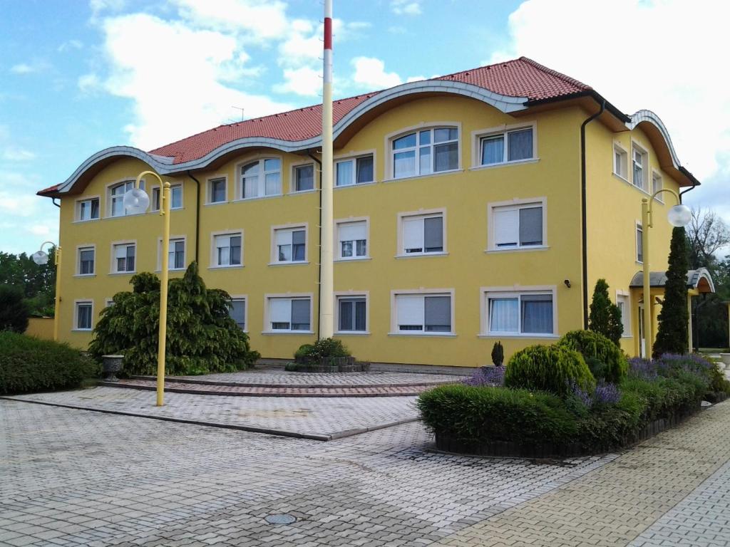 um edifício amarelo com um telhado vermelho em Leier Business Hotel em Gönyů
