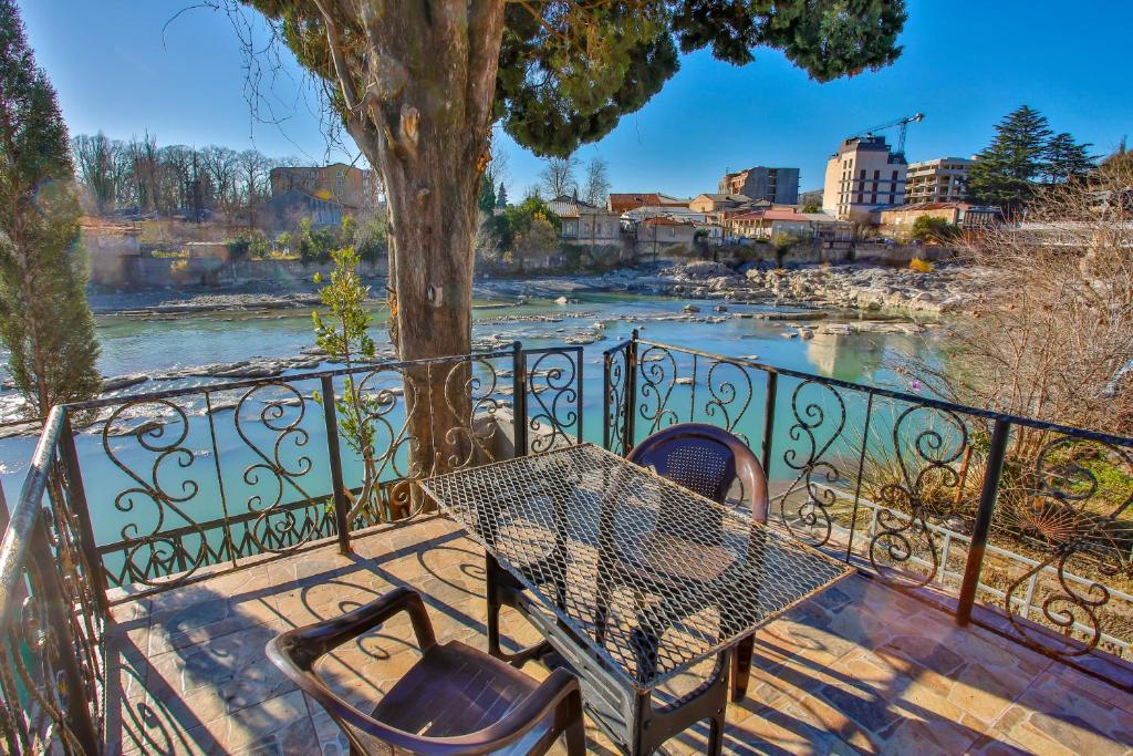 una mesa y sillas en un balcón con un río en Gantiadi en Kutaisi