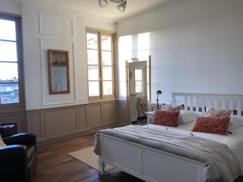 een slaapkamer met een groot wit bed met kussens bij Beautifully renovated rooms on Place New York in Angoulême