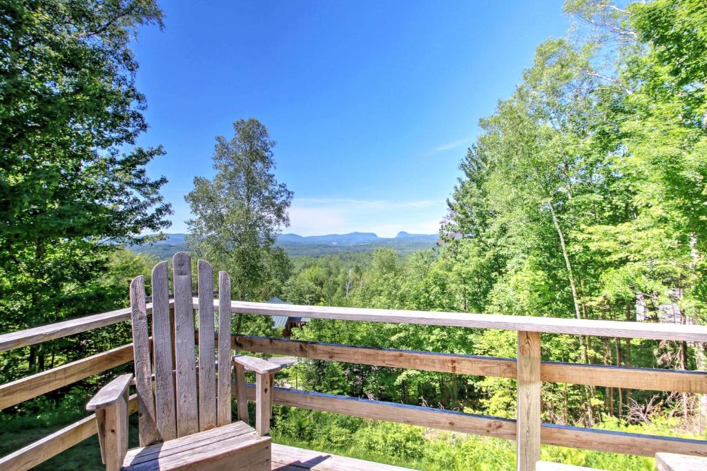 a wooden bench sitting on a deck with a view of trees at East Burke House with Deck Less Than 3 Mi to Kingdom Trails! in East Burke