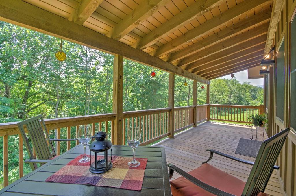 eine Veranda mit einem Tisch und Weingläsern darauf in der Unterkunft Scenic Fox Ridge Cabin on 4 Acres with Hot Tub! in Whittier