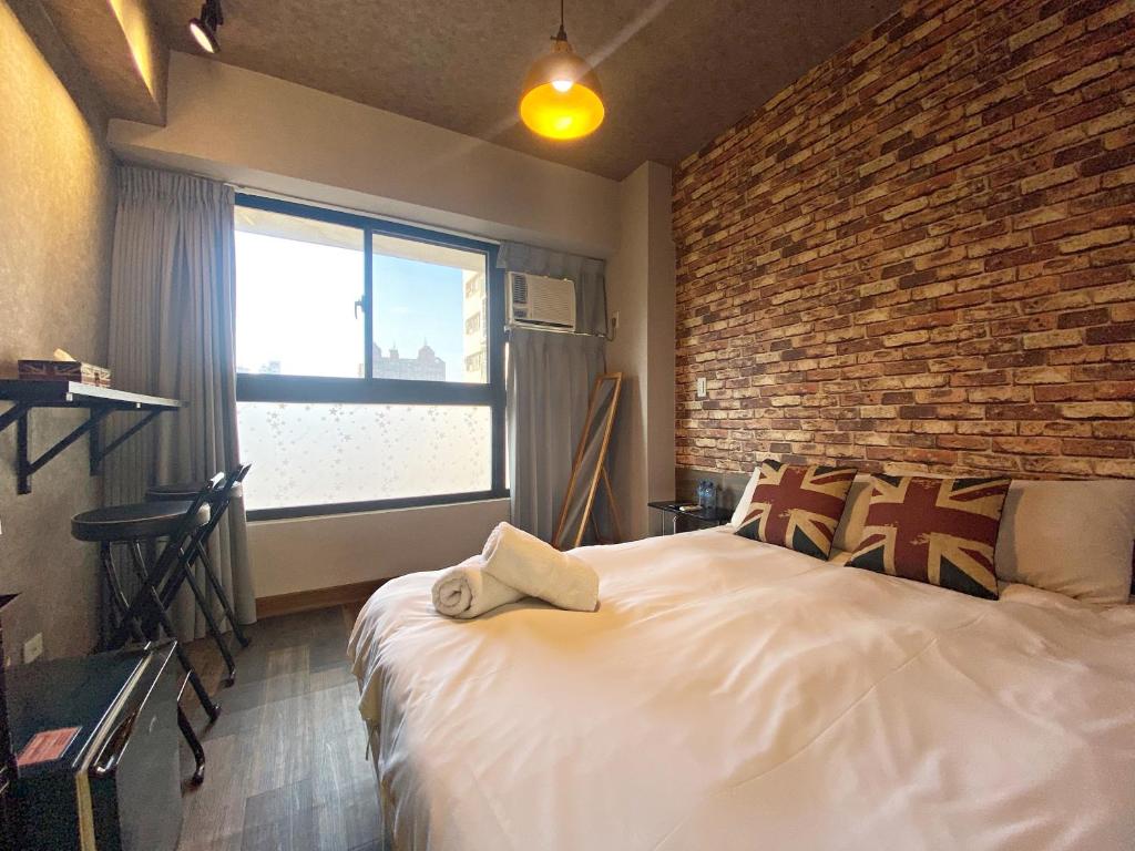 1 dormitorio con 1 cama grande y pared de ladrillo en Fengjia 101, en Taichung