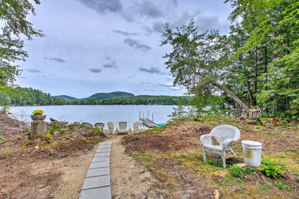 a row of chairs sitting on the shore of a lake at Hartford Cottage with Dock and Private BCH on Bear Pond in Hartford
