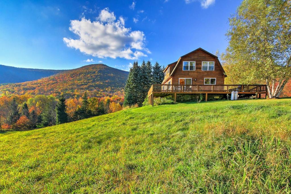 a house on top of a hill with a green field at Bearpen Lodge on 125 Acres - Near Belleayre Mtn! in Vega