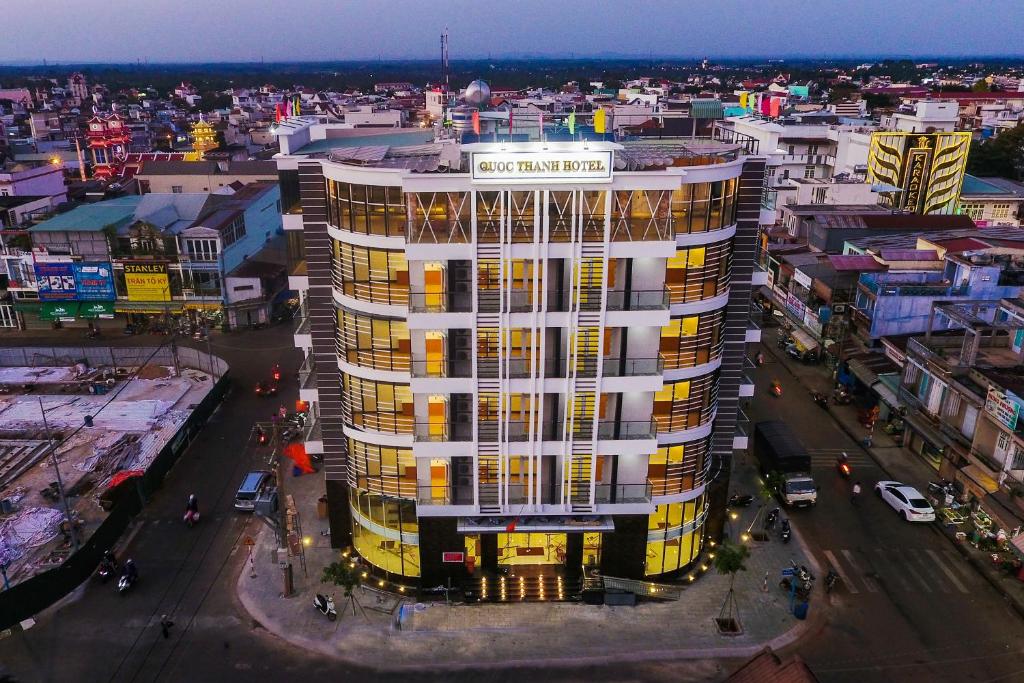 wysoki biały budynek z żółtymi oknami w mieście w obiekcie Quốc Thanh Hotel w mieście Long Khanh