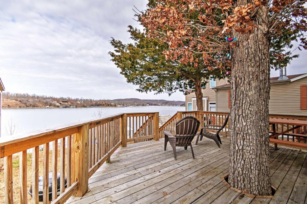 a wooden deck with two chairs and a tree at Cozy Camdenton Cottage with Deck and Boat Dock Access! in Camdenton