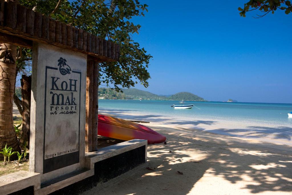 un panneau sur une plage avec un bateau dans l'eau dans l'établissement Koh Mak Resort, à Ko Mak