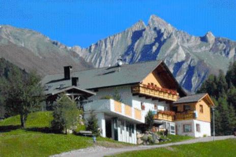 un grande edificio di fronte a una montagna di Unterhof a Riva di Tures