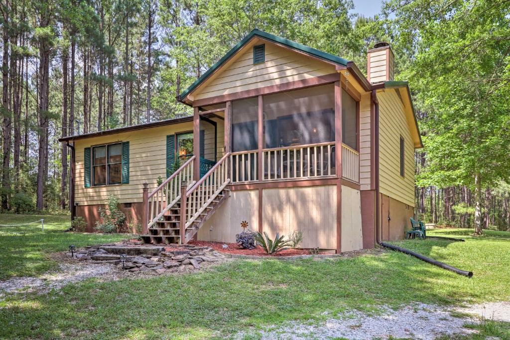 a small yellow house with a porch and a deck at Cozy Pine Mountain Cabin with Screened Porch and Yard! in Pine Mountain