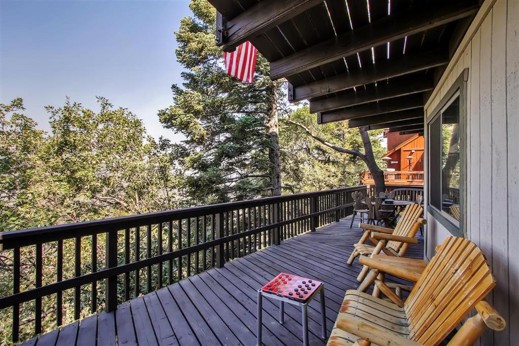 - une terrasse couverte avec 2 chaises et un drapeau américain dans l'établissement Family Cabin with Game Room Near Hiking and Skiing!, à Lake Arrowhead
