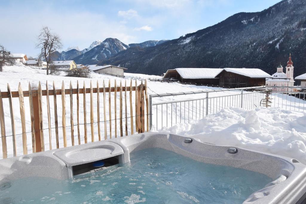 a hot tub in the snow with a fence at Ferienhaus Lurger in Strassen