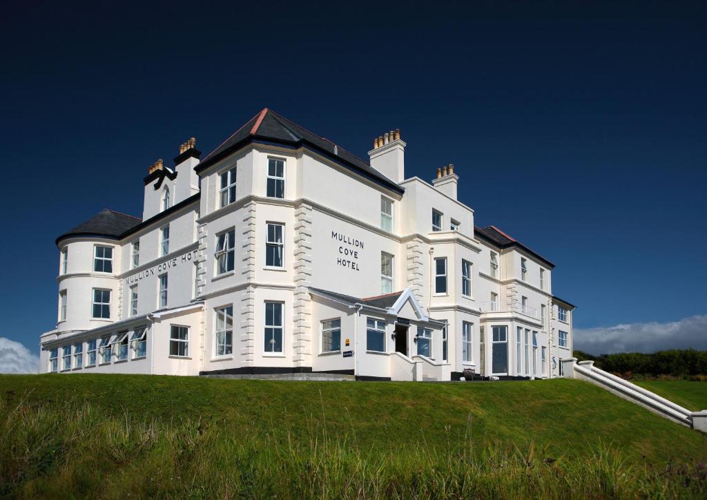 a large white house on top of a grassy hill at Mullion Cove Hotel & Spa in Mullion