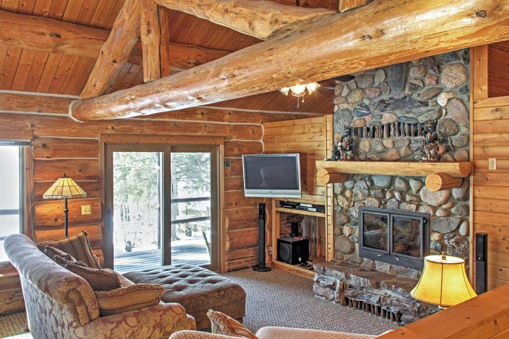 sala de estar con chimenea de piedra y TV en Wonderful Home on Sand Lake with Expansive Porch!, en Squaw Lake
