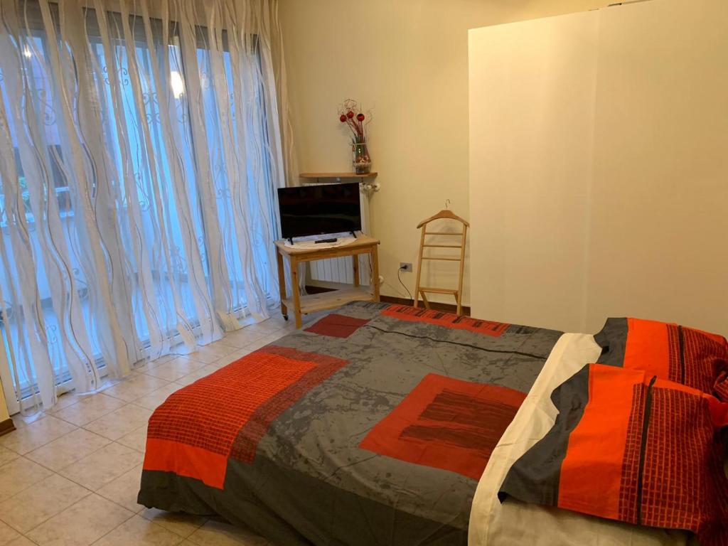 1 dormitorio con cama, TV y cortinas en Bicocca Flat F, en Milán
