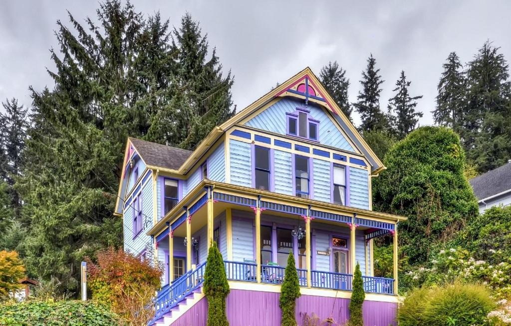 een blauw en geel huis met een hek bij Astoria Painted Lady Historic Apt with River View! in Astoria, Oregon
