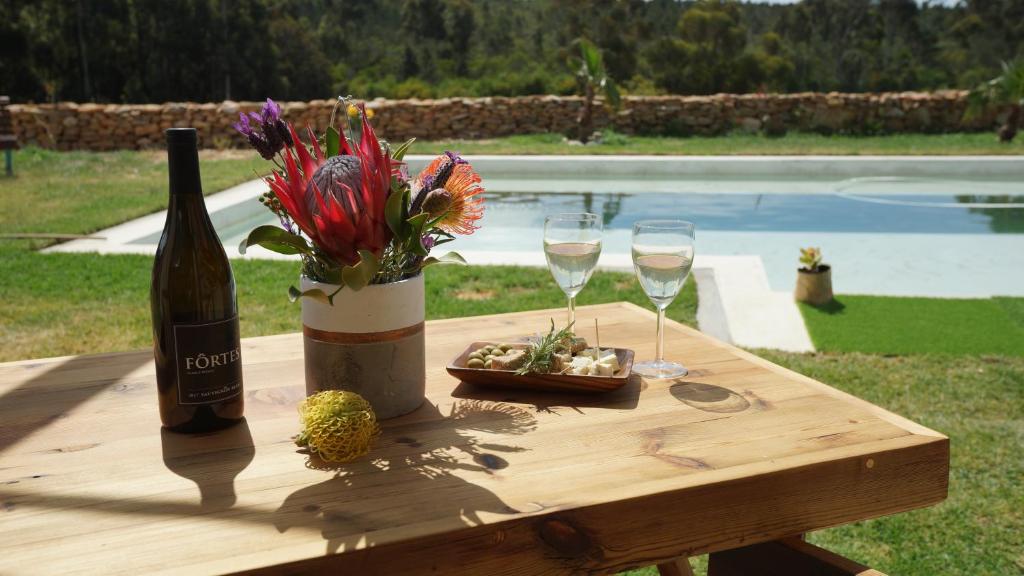 a wooden table with a bottle of wine and two glasses at Stellar Overberg Travellers Lodge in Napier