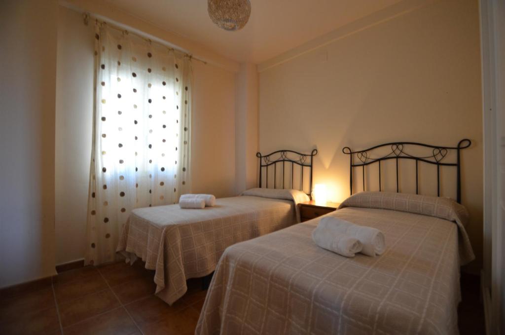 two beds in a room with a window at Apartamentos Solmares in Isla Canela