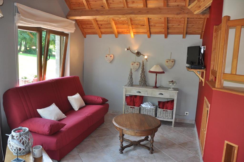 een woonkamer met een rode bank en een tafel bij Gite du vieux pommier in Herbeumont