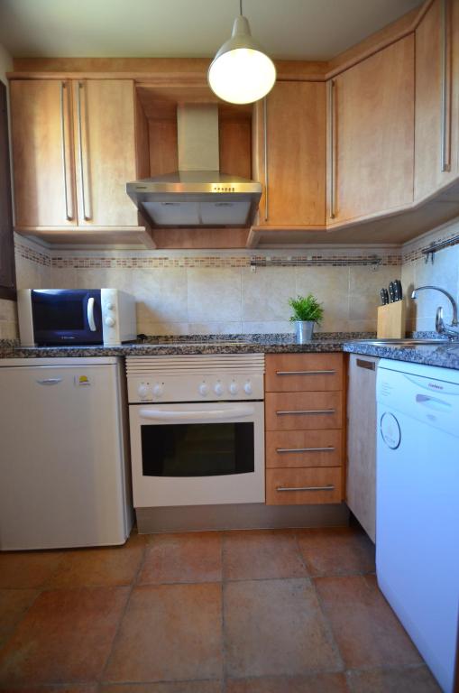 a kitchen with wooden cabinets and a white stove top oven at Apartamentos Solmares in Isla Canela