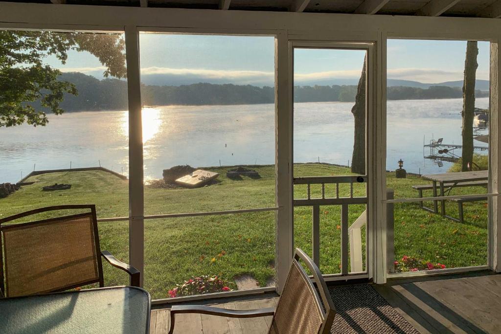 un porche cubierto con vistas al agua en Family Lake House with Paddleboards and Fire Pit!, en Tully