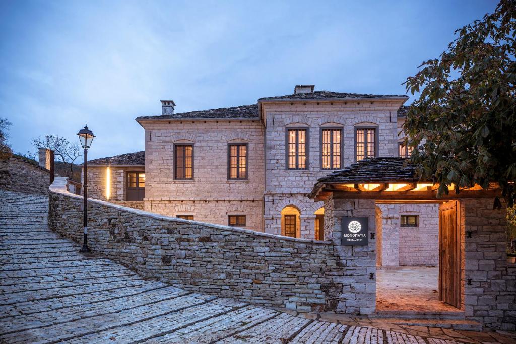 a large stone house with a brick wall at Monopatia Resort in Ano Pedina