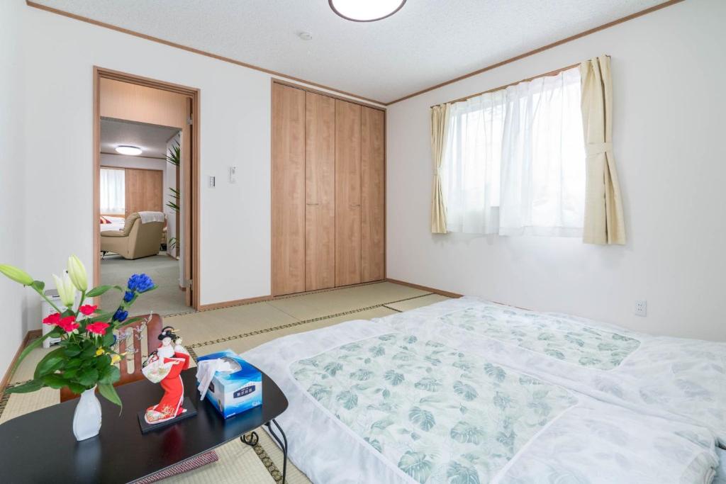 a bedroom with a bed and a table with a vase of flowers at Travel Palace Miyuki (Yomiuri Shimbun) / Vacation STAY 5684 in Kawaguchi