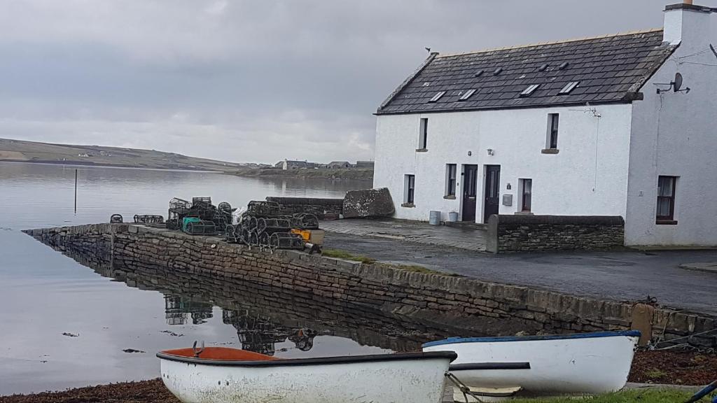 a house and some boats in the water at 2 The Noust Self Catering in Saint Margarets Hope