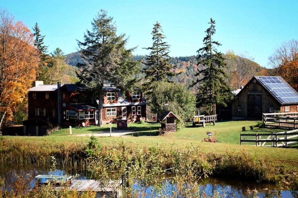 ein Haus auf einem Feld neben einem Wasserkörper in der Unterkunft Chester Farmhouse on 100 Acres, 15 Min to Okemo! in Chester